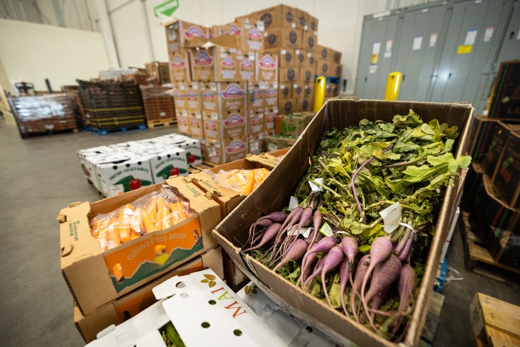 Fresh produce stacked in a Sharing Excess warehouse with a donations sign